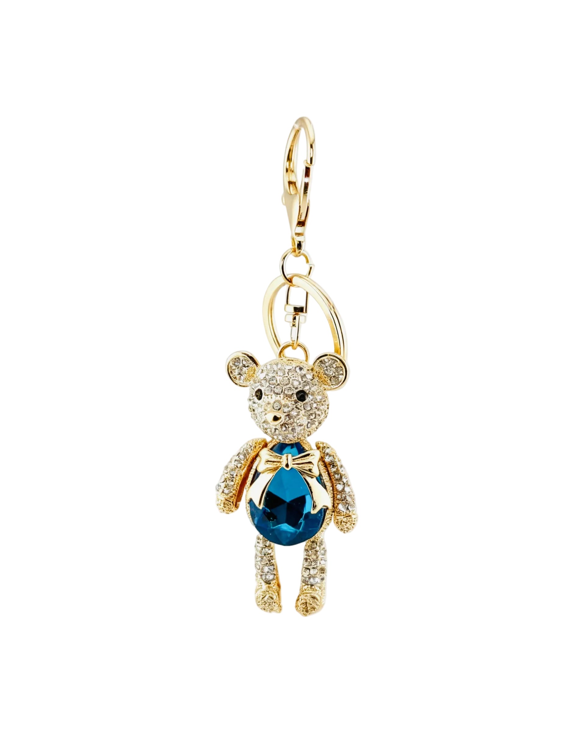 A gold-tone teddy bear charm keychain featuring a large faceted blue gemstone on the belly and clear rhinestone detailing, shown against a light gray background.