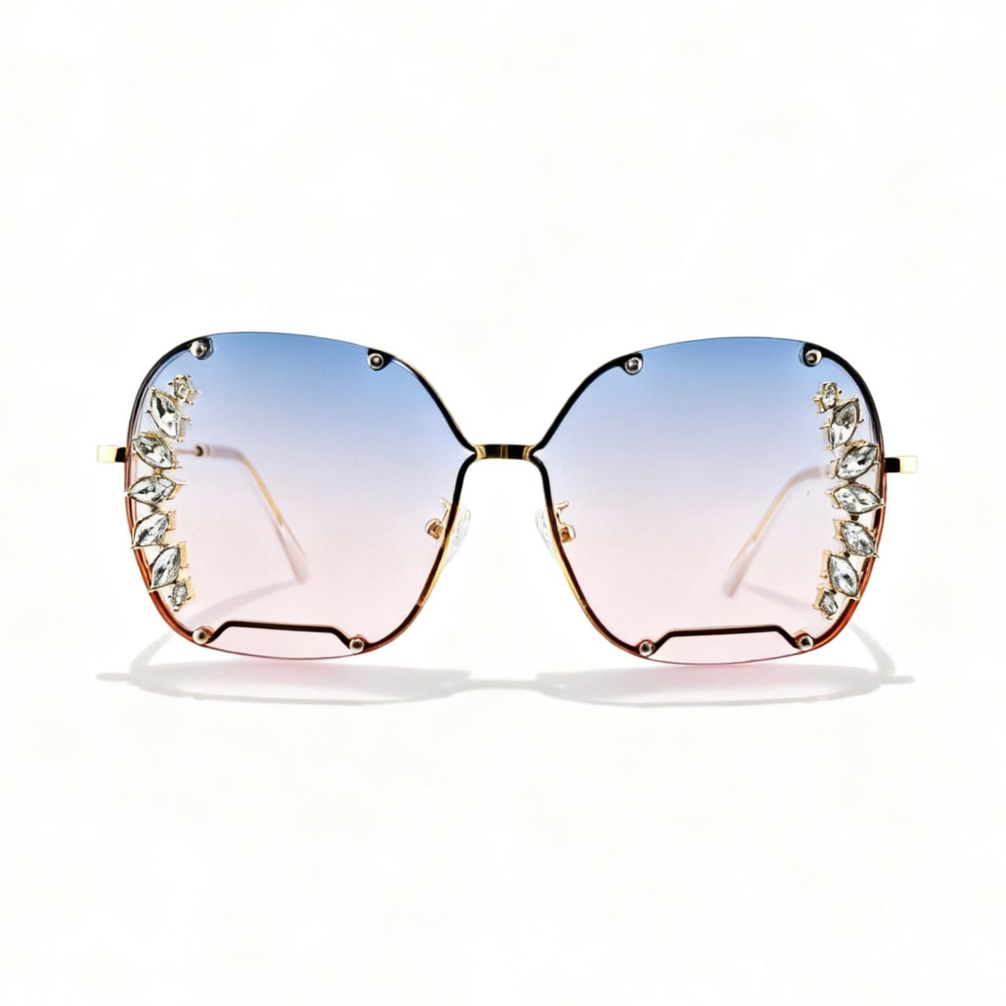 Oversized square sunglasses with a gold-tone metal frame, decorative crystal embellishments on the outer corners, and gradient lenses that fade from light blue at the top to pale pink at the bottom.