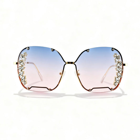 Oversized square sunglasses with a gold-tone metal frame, decorative crystal embellishments on the outer corners, and gradient lenses that fade from light blue at the top to pale pink at the bottom.