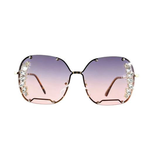 Oversized square sunglasses with gradient pink-to-purple lenses, decorated with clear rhinestones along the outer edges of the frames, shown against a plain white background.