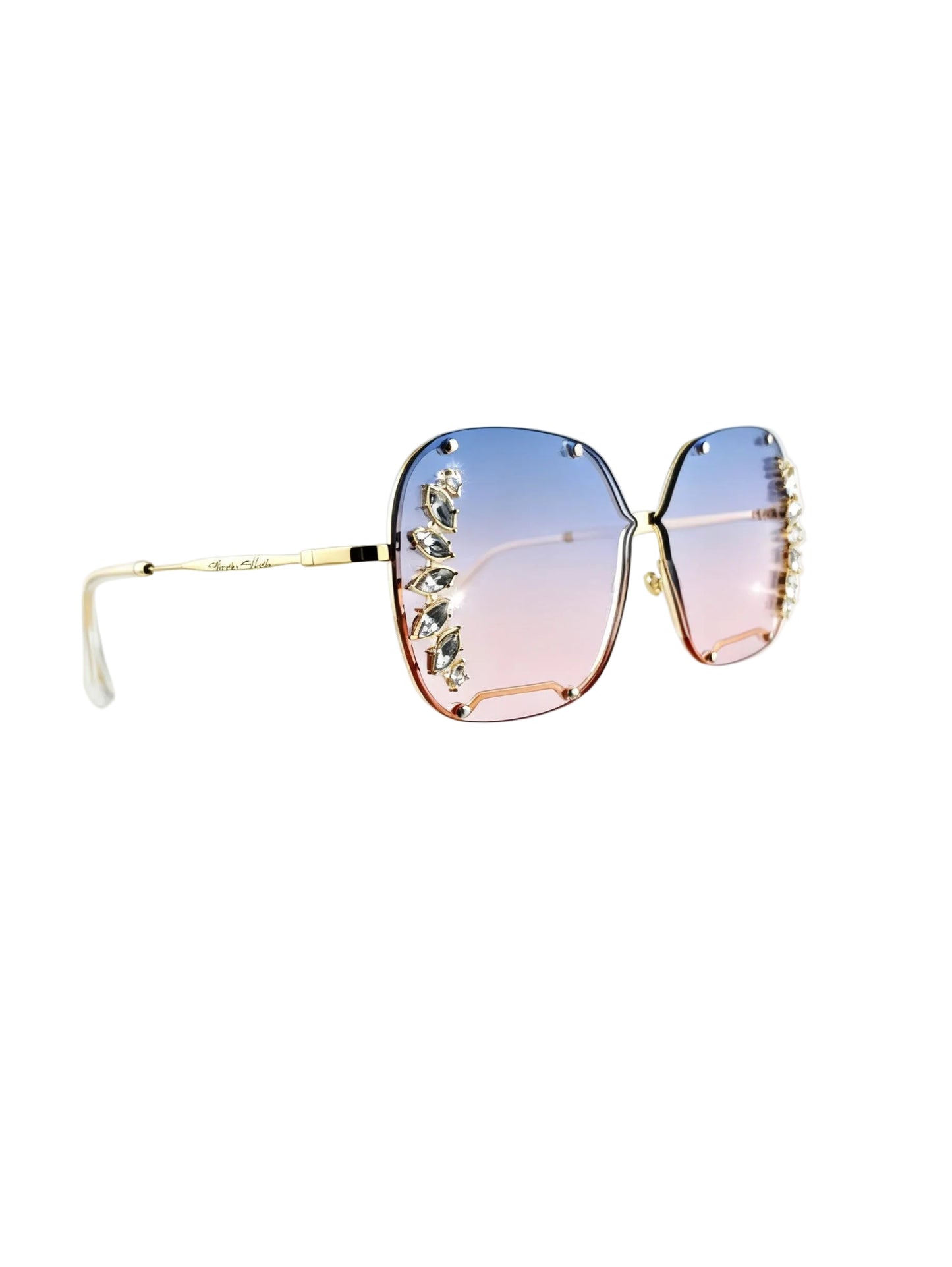 Oversized square sunglasses with gradient blue-to-pink lenses, gold metal frames, and crystal embellishments along the outer edges, shown on a white background.