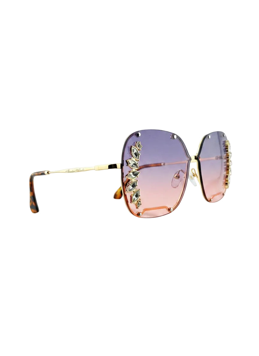 Oversized square sunglasses with a gold-tone metal frame, decorative crystal embellishments on the outer edges, and gradient lenses that fade from lavender-purple to soft pink.